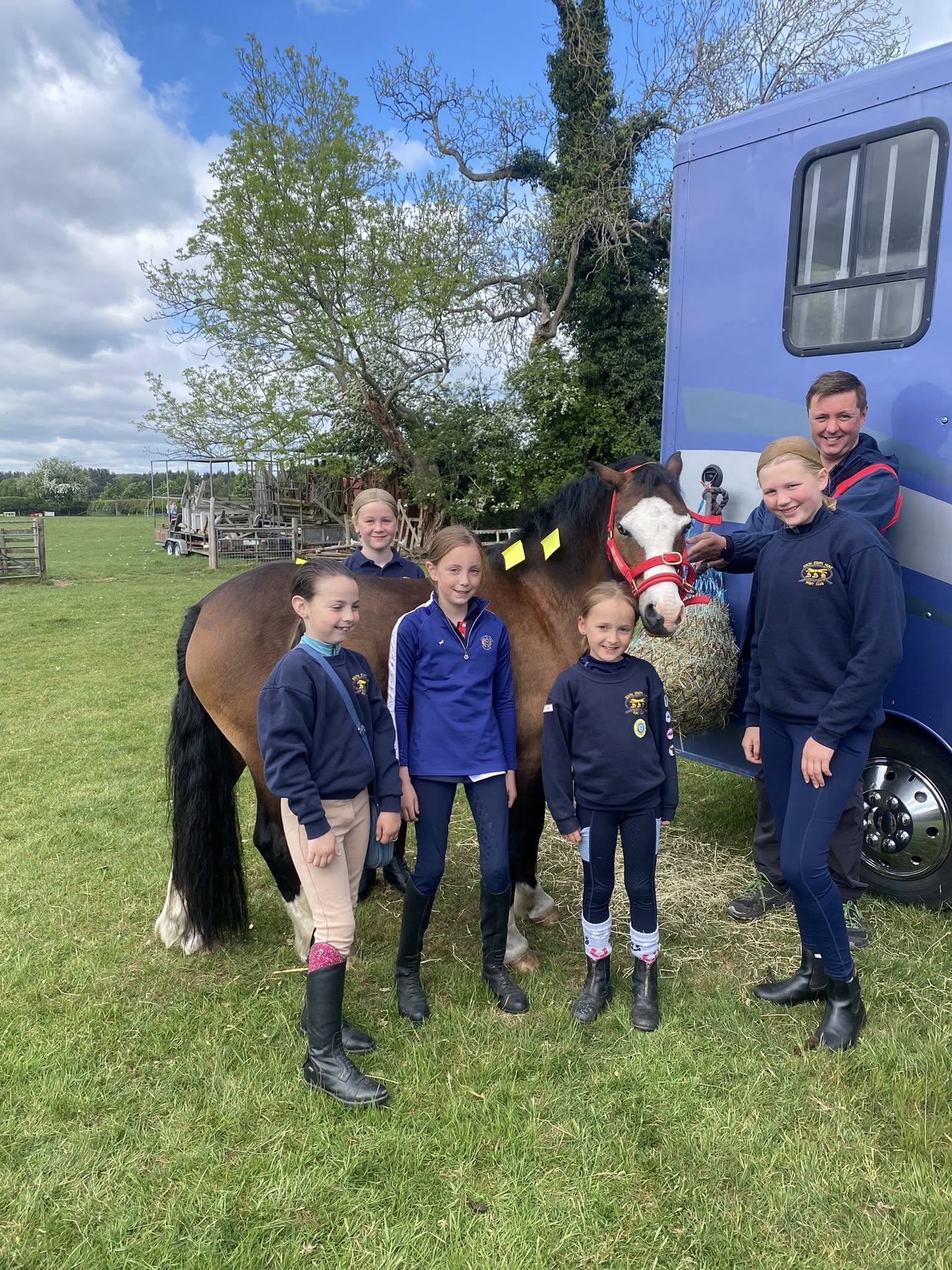 Four girls, a man and a pony standing in front of a lorry