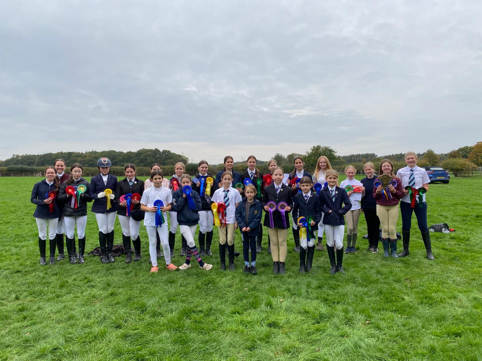 A group of girls standing in a field holding rosettes